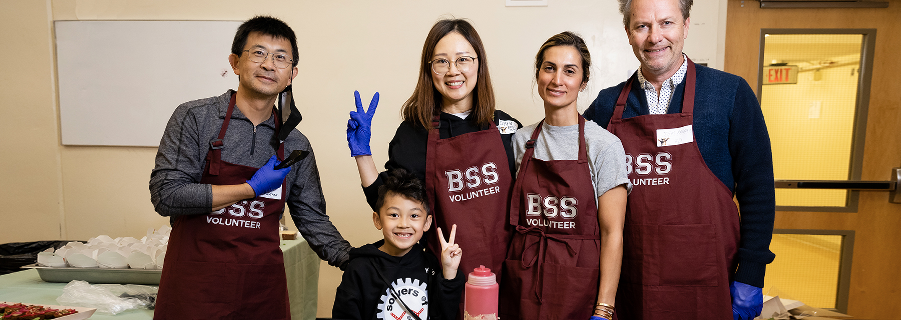 A group of BSS parents in branded aprons volunteer at the bake sale.