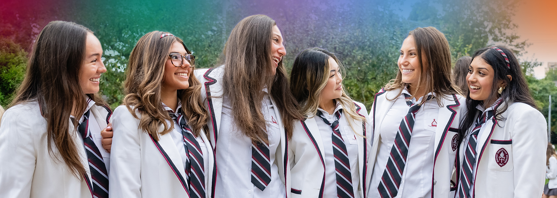 Six BSS 2025 grads wearing white uniforms stand arm-in-arm, smiling.