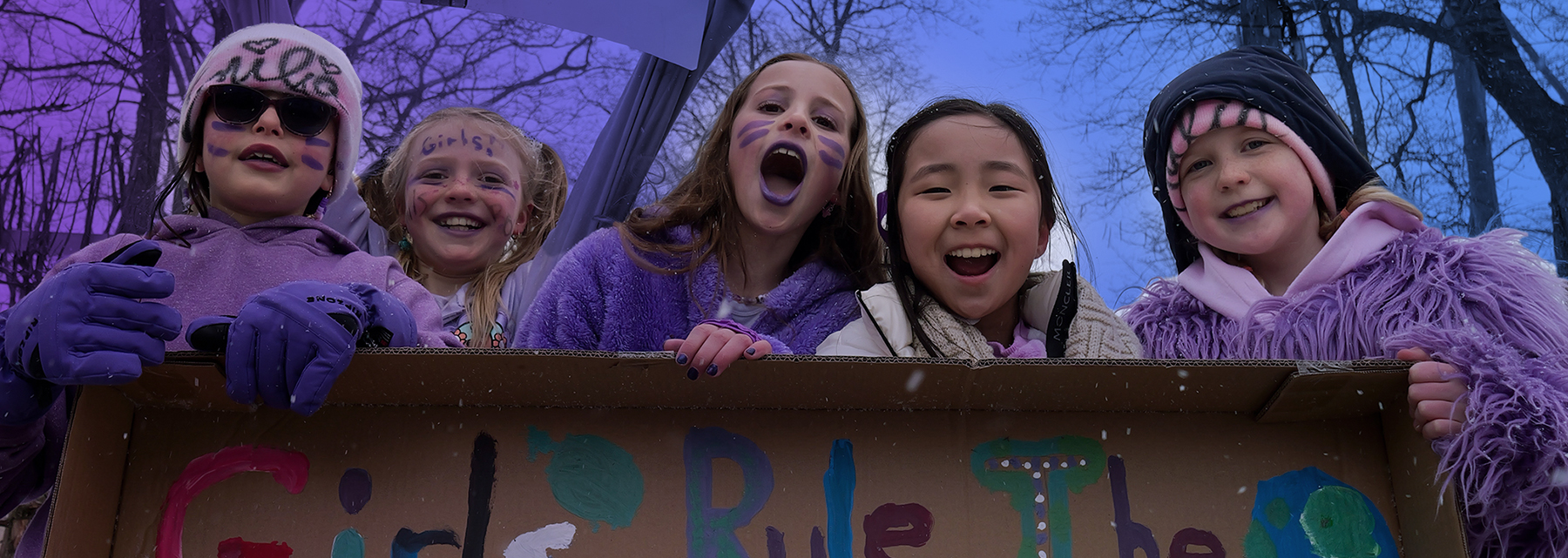 Five BSS junior school students holding a "Girls Rule" sign and laughing.